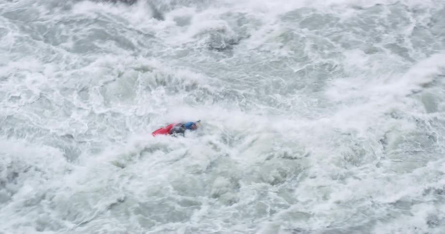 A kayaker struggles to stay upright as the violent waves of a river push around their kayak