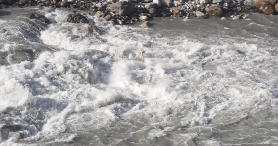 Person navigates kayak through huge fast moving rapids in river