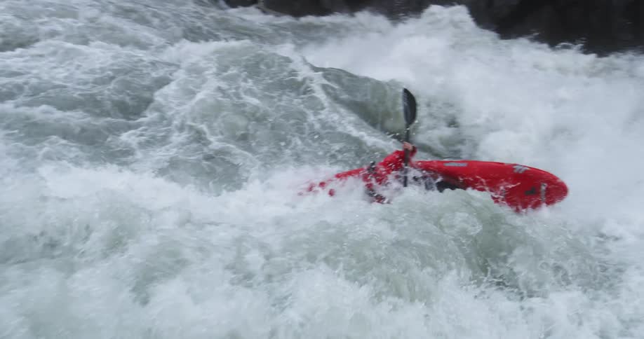 A kayaker struggles to paddle his kayak through the raging waters of a river