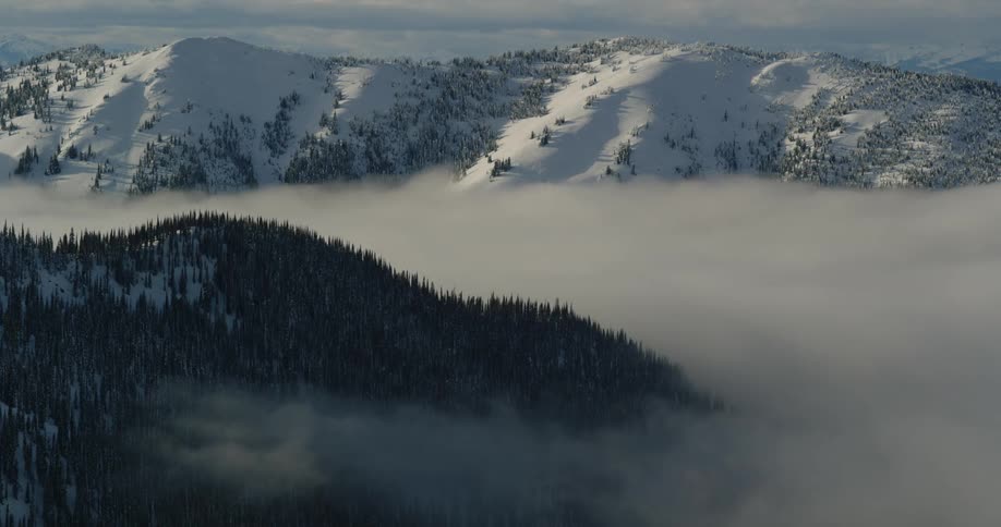 Fog fills valley below snow covered mountains