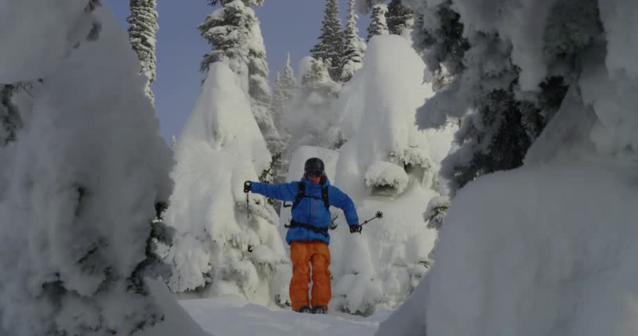 A person with a backpack helmet and goggles skiing and jumping on snow