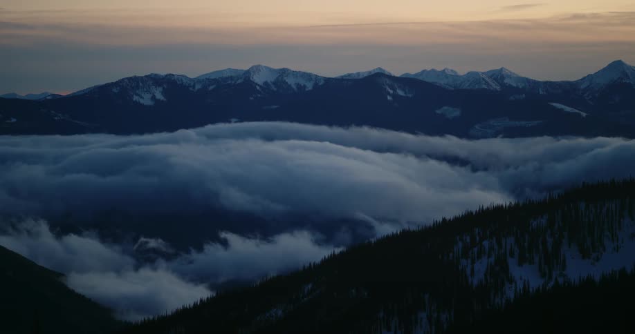 Clouds floating over snowy mountains at sunset