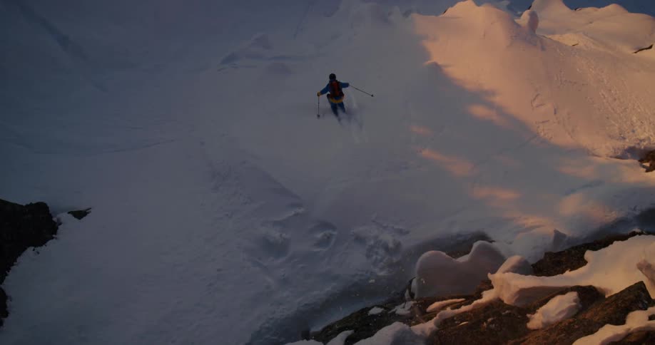 A skier going over a jump in snowy mountains