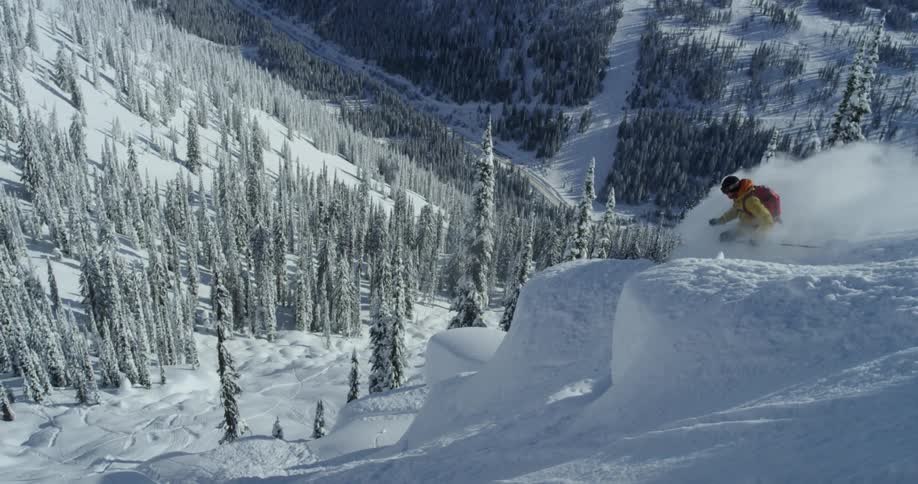 Person skis down steep slope in forest