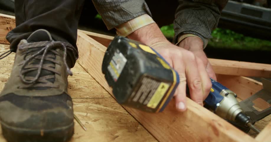 A person using a power tool to drill into wood dolly shot