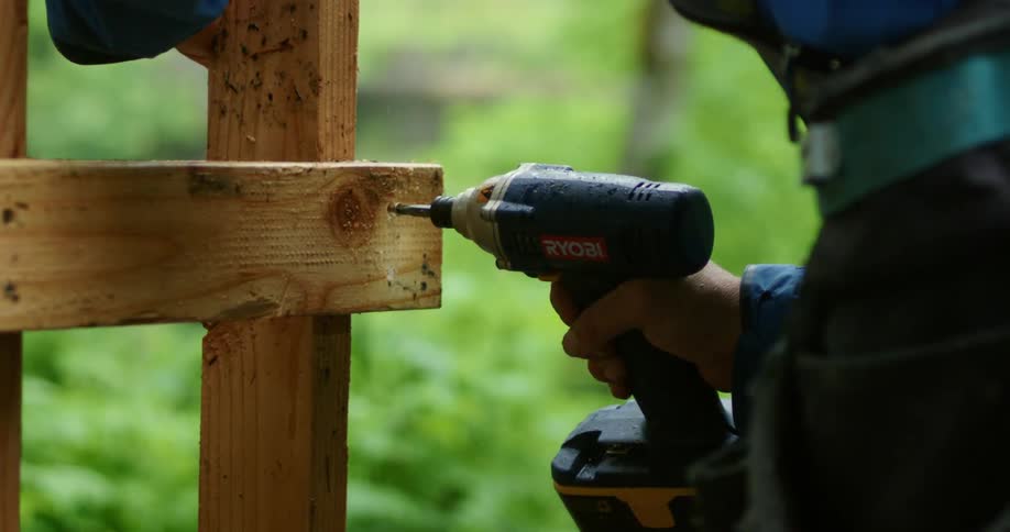 Man secures two posts together with screw driven by drill