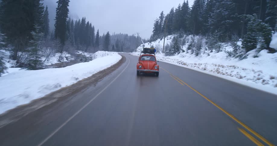 An old VW Bug driving down a winter road