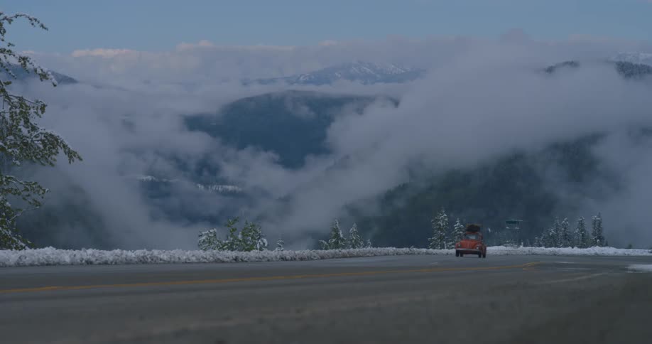 A vintage car driving on a snowy mountain road
