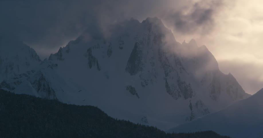 Heavy clouds above snowy mountains at dawn