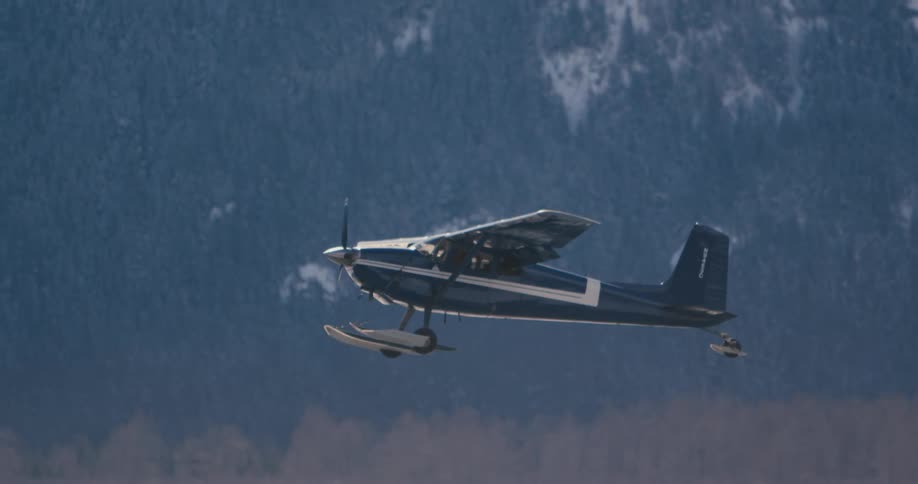 Small airplane takes off from snowy field in front of mountain