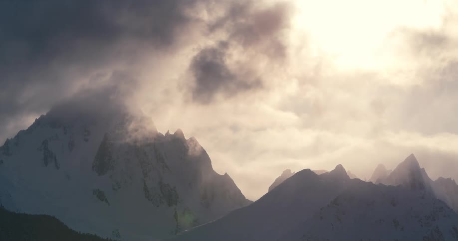 Clouds floating over a snowy mountain range on a winter day