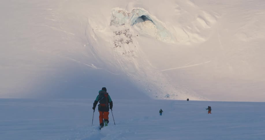 A person with a backpack a hat and skis hiking on snow