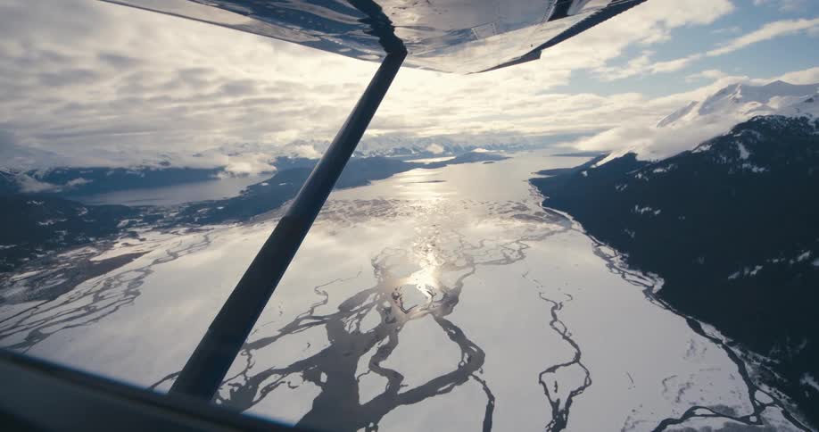 Frozen river or glacier between mountains seen from an airplane