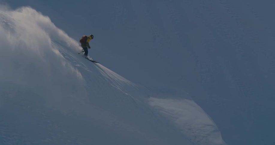 A person with a backpack and a helmet skiing down a snowy slope