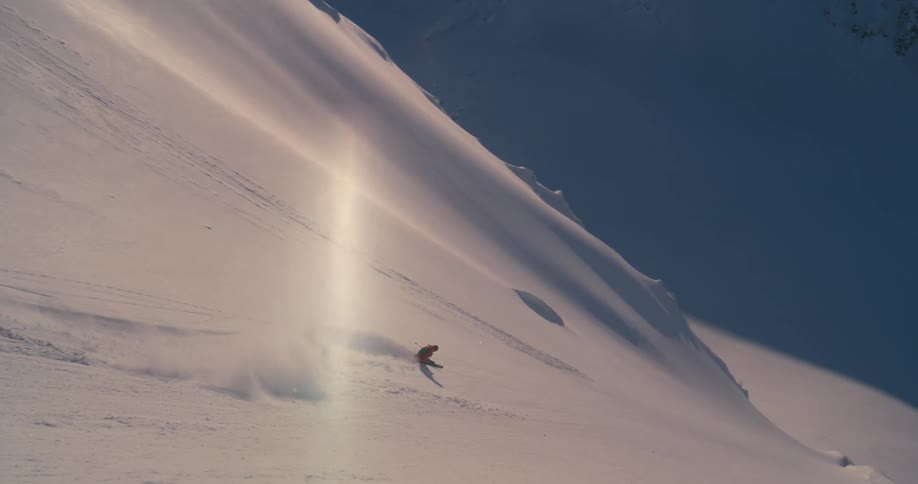 A skier descends a smooth mountain slope on a sunny day