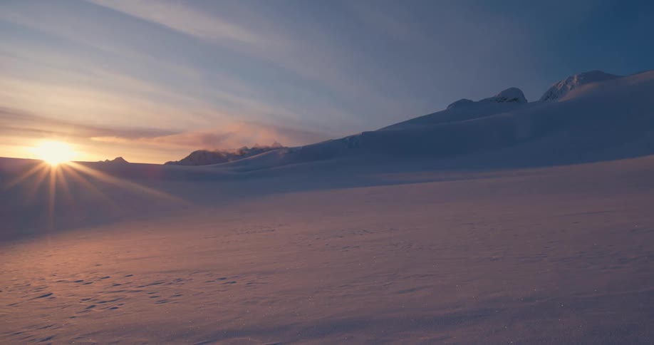The sun setting over snowy mountains in nature