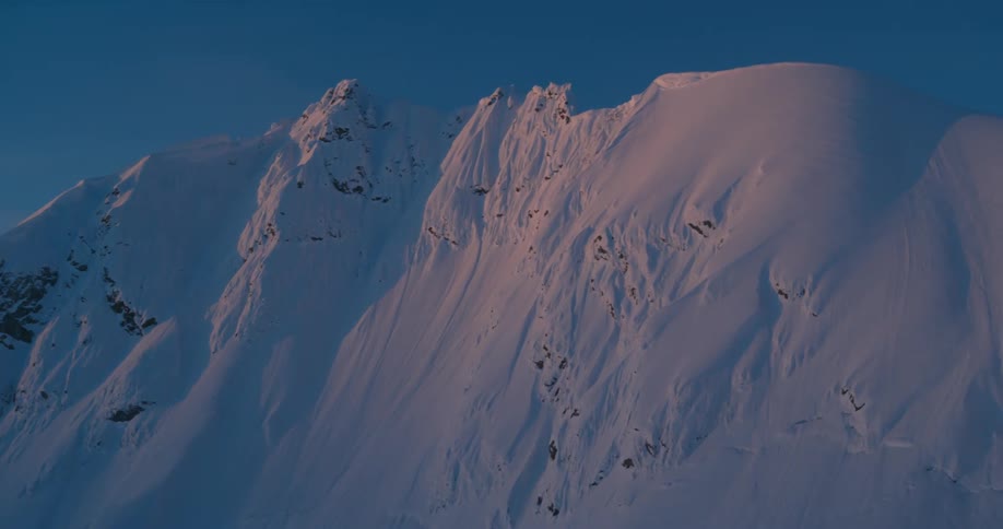 A snow covered mountain ridge in the evening