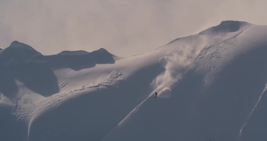 Downhill skier on tall steep mountainside