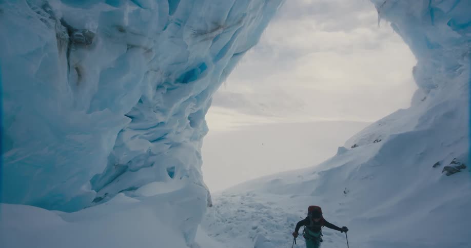 Person cross country skiing through ice cave in mountains