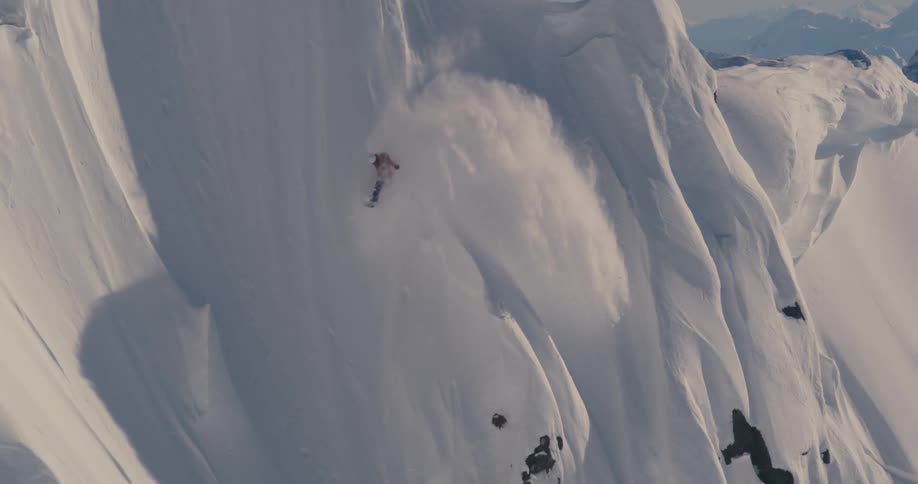 A person with a backpack and helmet skiing down a snowy slope with the sky in the background