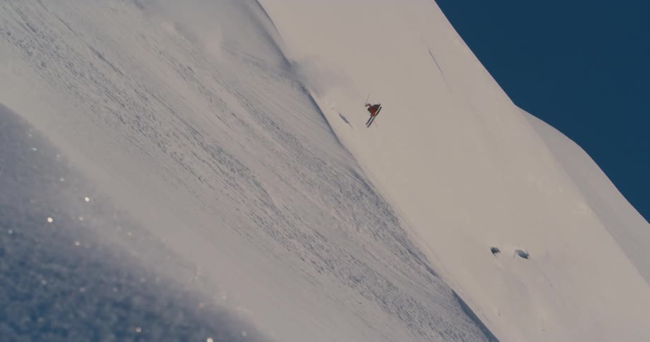 A skier speeding down a snowy mountainside on a winter day