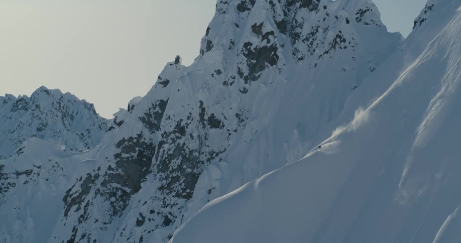A skier skis down the side of a mountain range