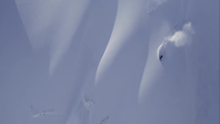 Aerial of skier making huge turns down a big mountain