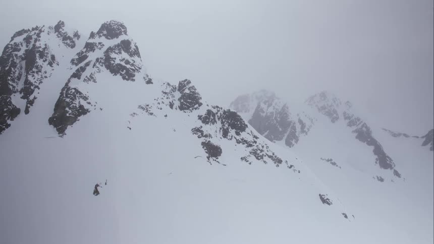 Aerial of snowy mountains draped in clouds