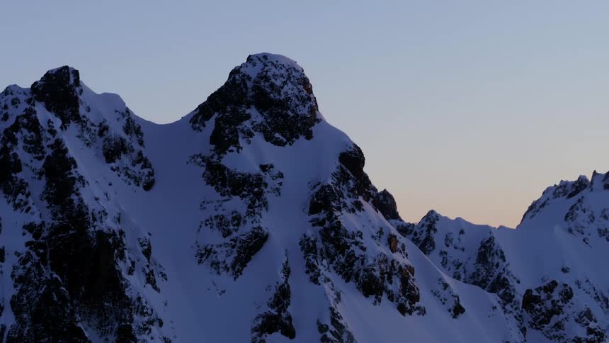 Aerial of a huge snowy mountain range in the purple dusk