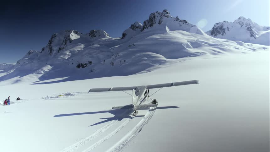 Small airplane in snow near base camp in mountain range