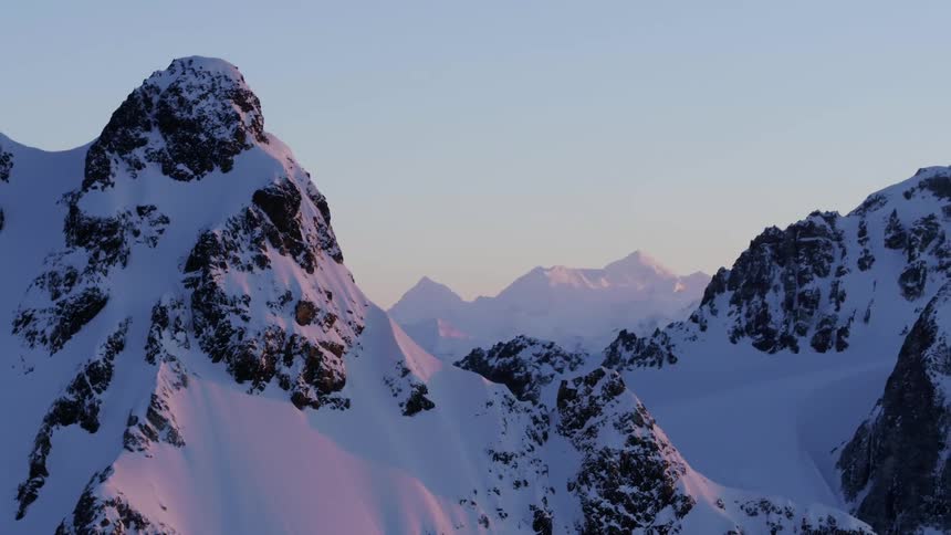 Aerial of a massive mountain range in pink alpenglow