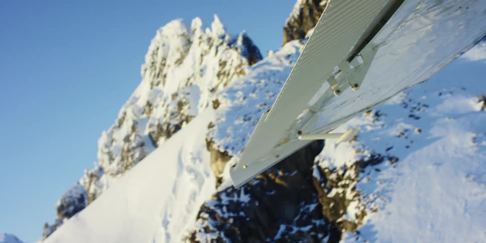 Rugged rocks and snow capped peaks seen from a plane