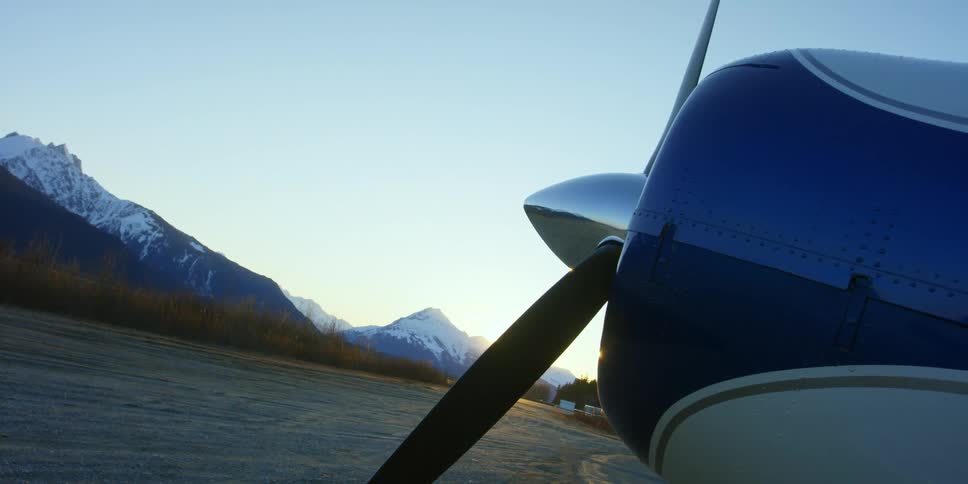 The propeller of a plane in a field beneath snowy mountains