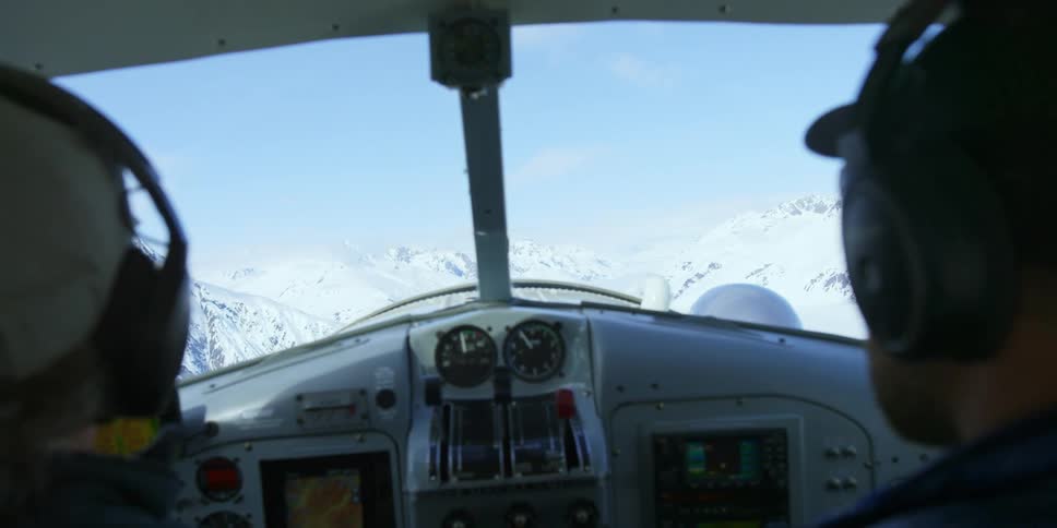 Two men with hats and sunglasses in the cockpit of a plane