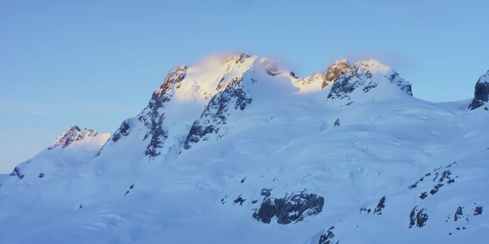 A snow covered mountain ridge under a clear daytime sky