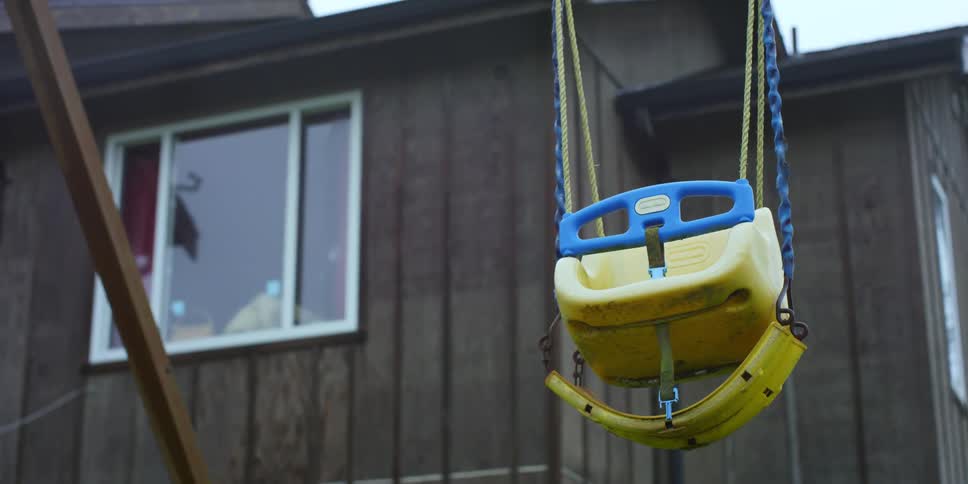 Yellow swing for babies hangs motionless outside the house