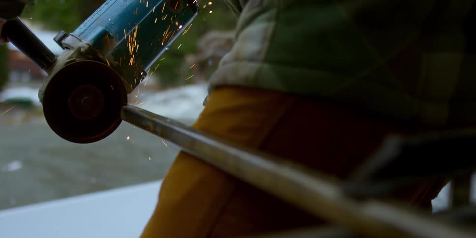 A person cuts a pole with a angle grinder