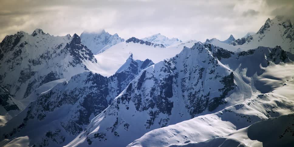 Snowy mountain peaks under clouds