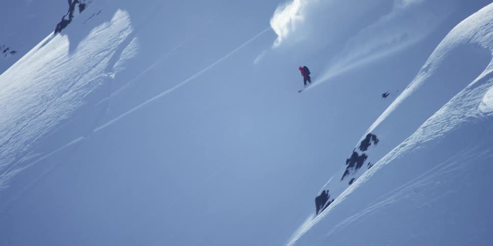 A man is snowboarding down a mountain