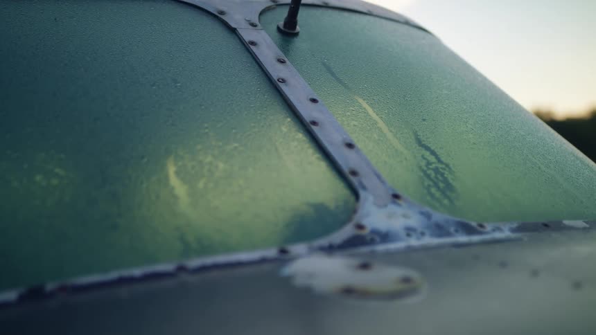 An old aircrafts windshield is covered with dew in the early morning