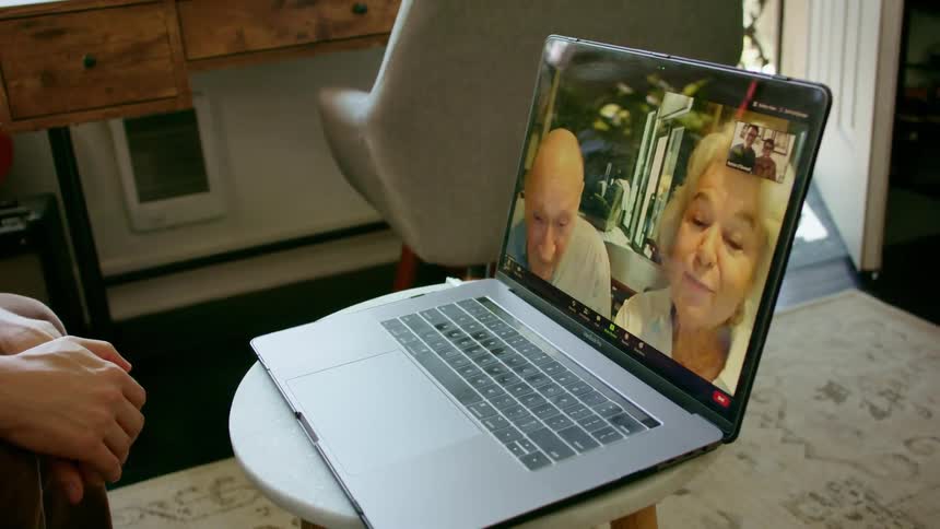 Elderly couple on a video call with their family on a laptop at home