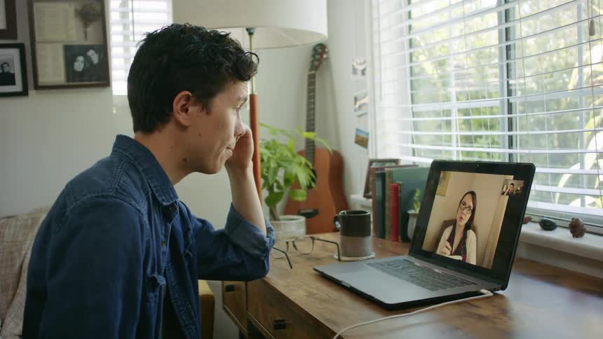 A man at home video chats with a woman on his laptop