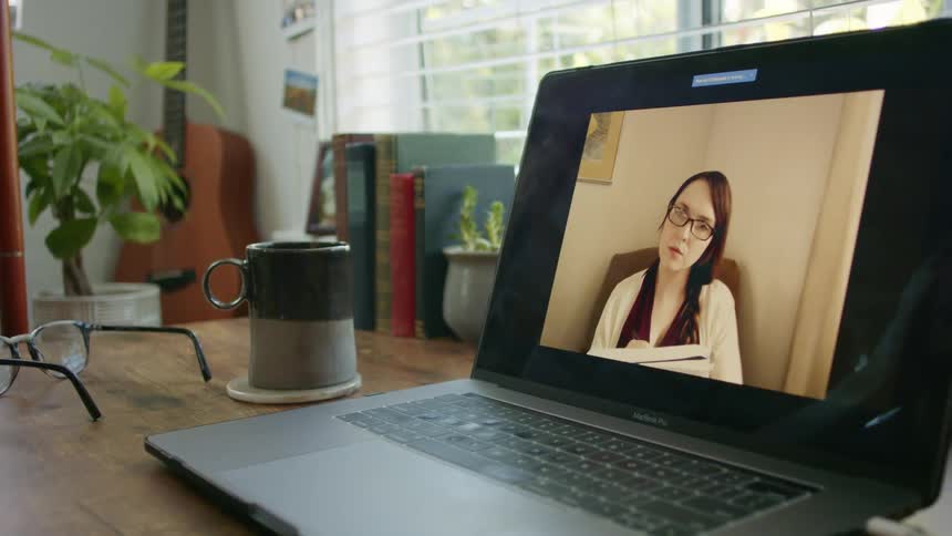 A woman is talking on the laptop screen