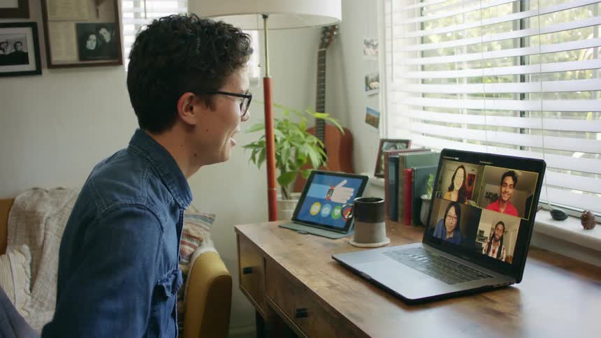 Working remotely drinking coffee during zoom meeting with colleagues