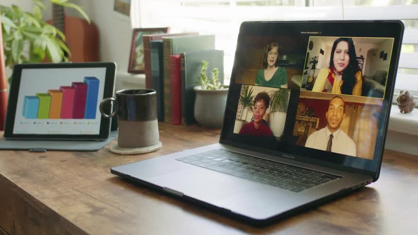 A laptop displaying four people having a video conference