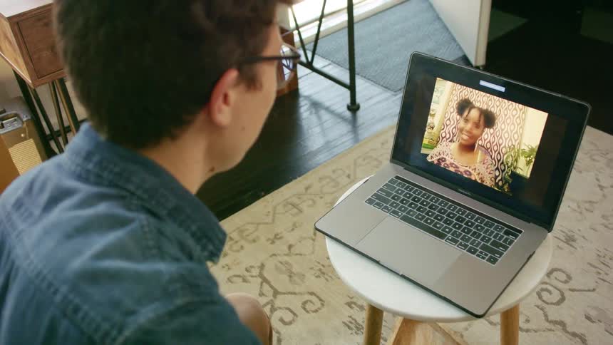 A man at home video chats with a woman on his laptop