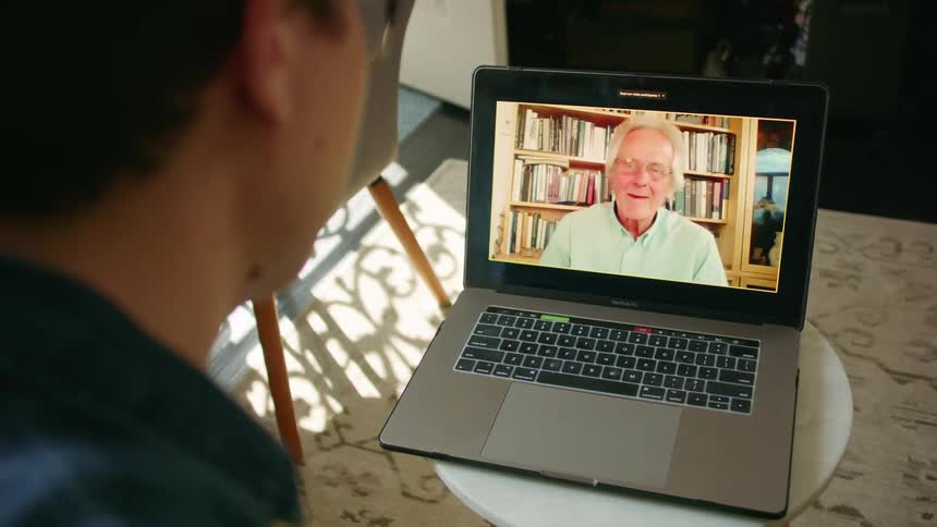 A young man at home video chat with an elderly man on a laptop