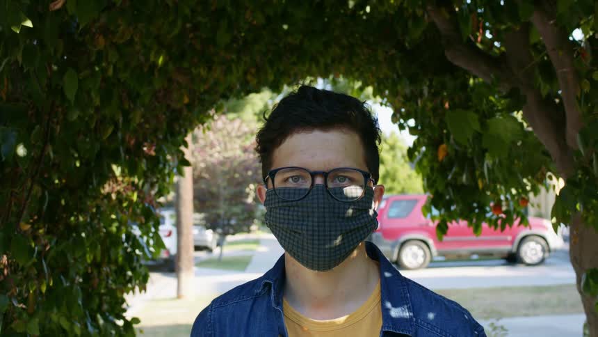 A man is outdoors while wearing a face mask