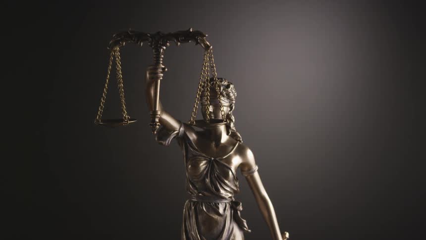 A small statue of a blindfolded woman holding a balance represents justice