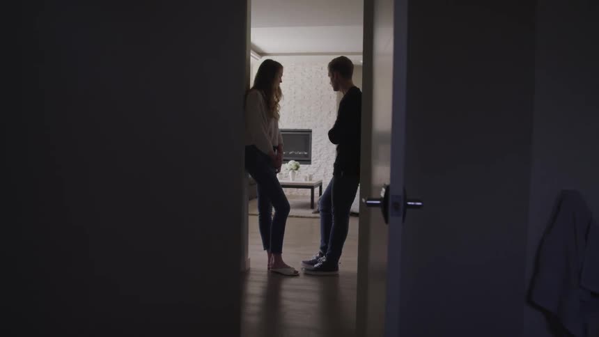 A man and woman are talking inside a house